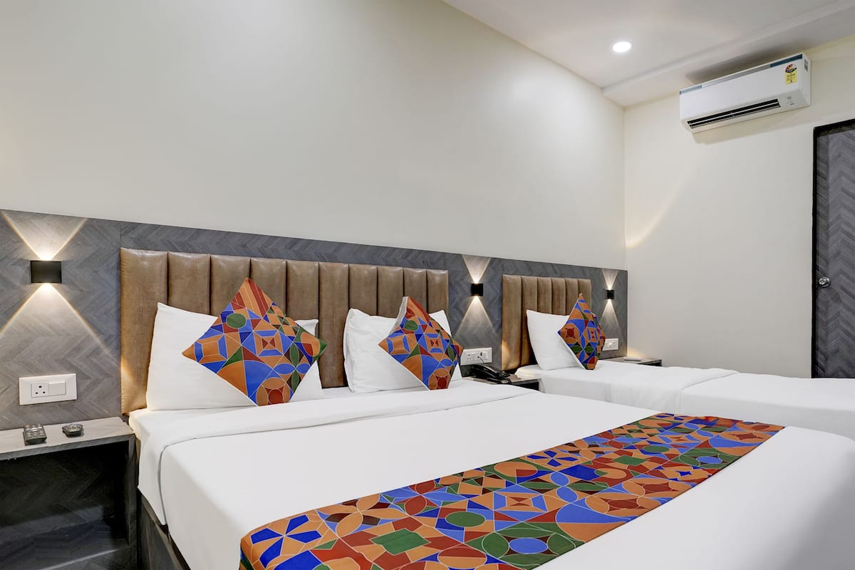 Habitación de hotel con una cama grande, dos mesitas de noche y un cabecero con diseños geométricos.