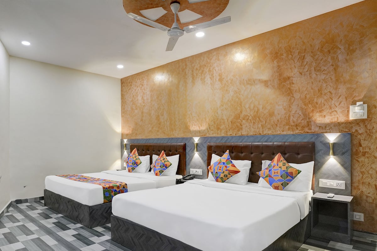 Habitación de hotel con dos camas, ventilador de techo y pared con estampado.