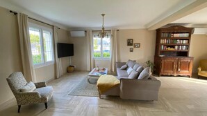 Uma sala de estar com sofá, poltrona e estante.