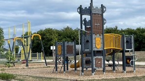 Um parquinho com uma estrutura de recreação com tema de castelo, incluindo escorregadores e elementos de escalada.