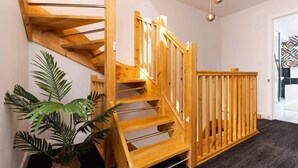 Eine Holztreppe mit Handlauf, ein dunkel teppichbelagter Boden und ein Blumentopf.