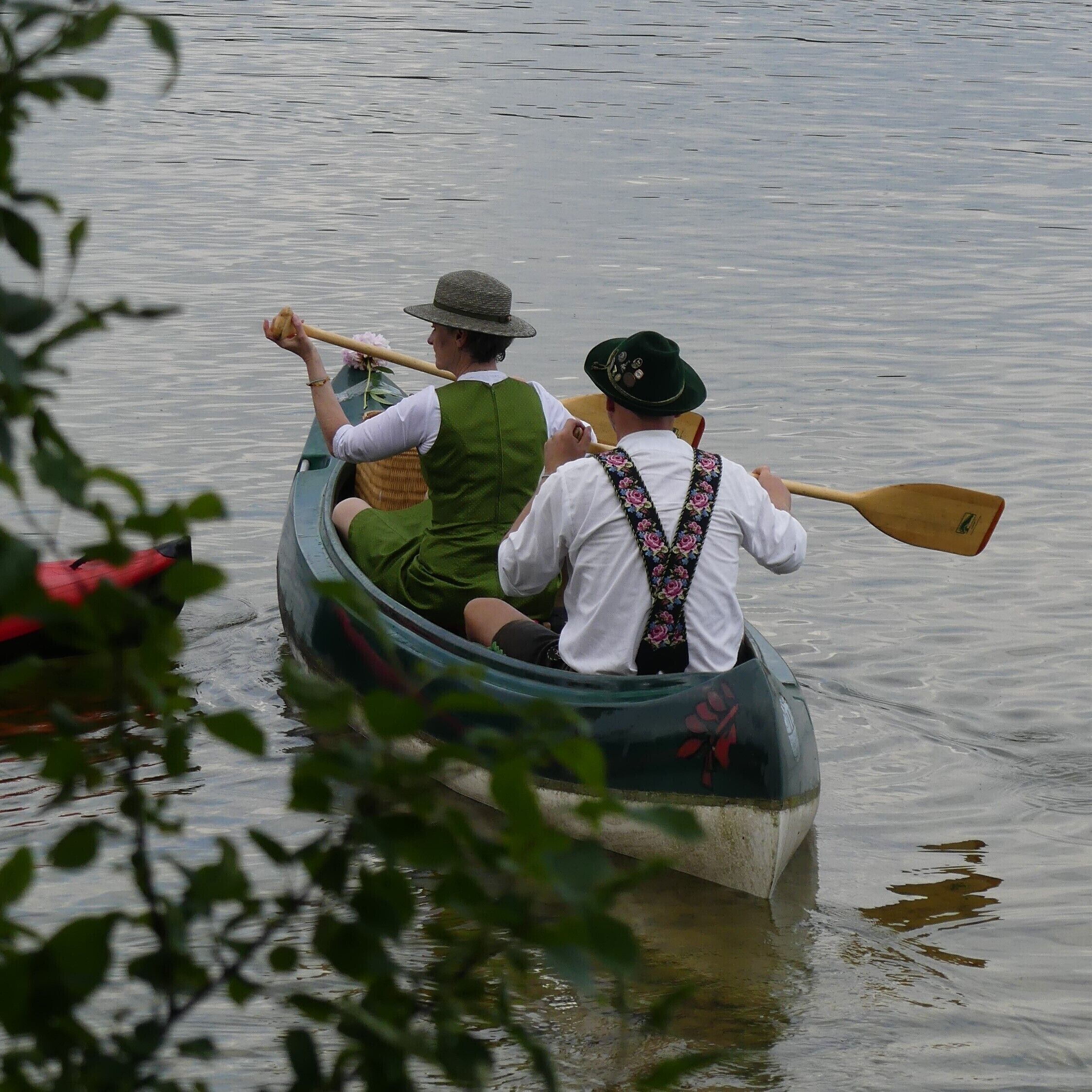 Dos personas en un bote estrecho sobre aguas tranquilas.