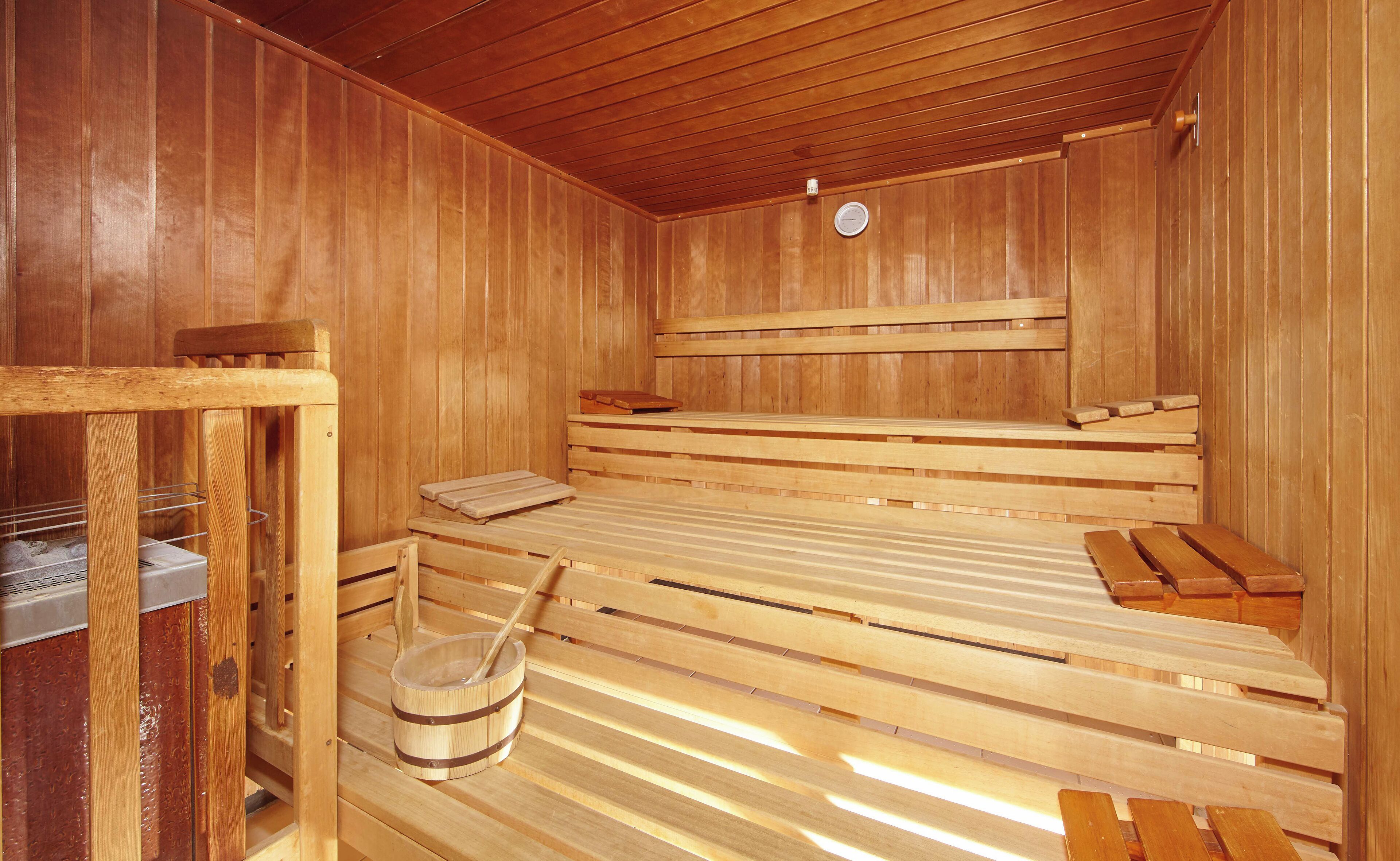 Una sauna de madera con bancos y un balde de madera.