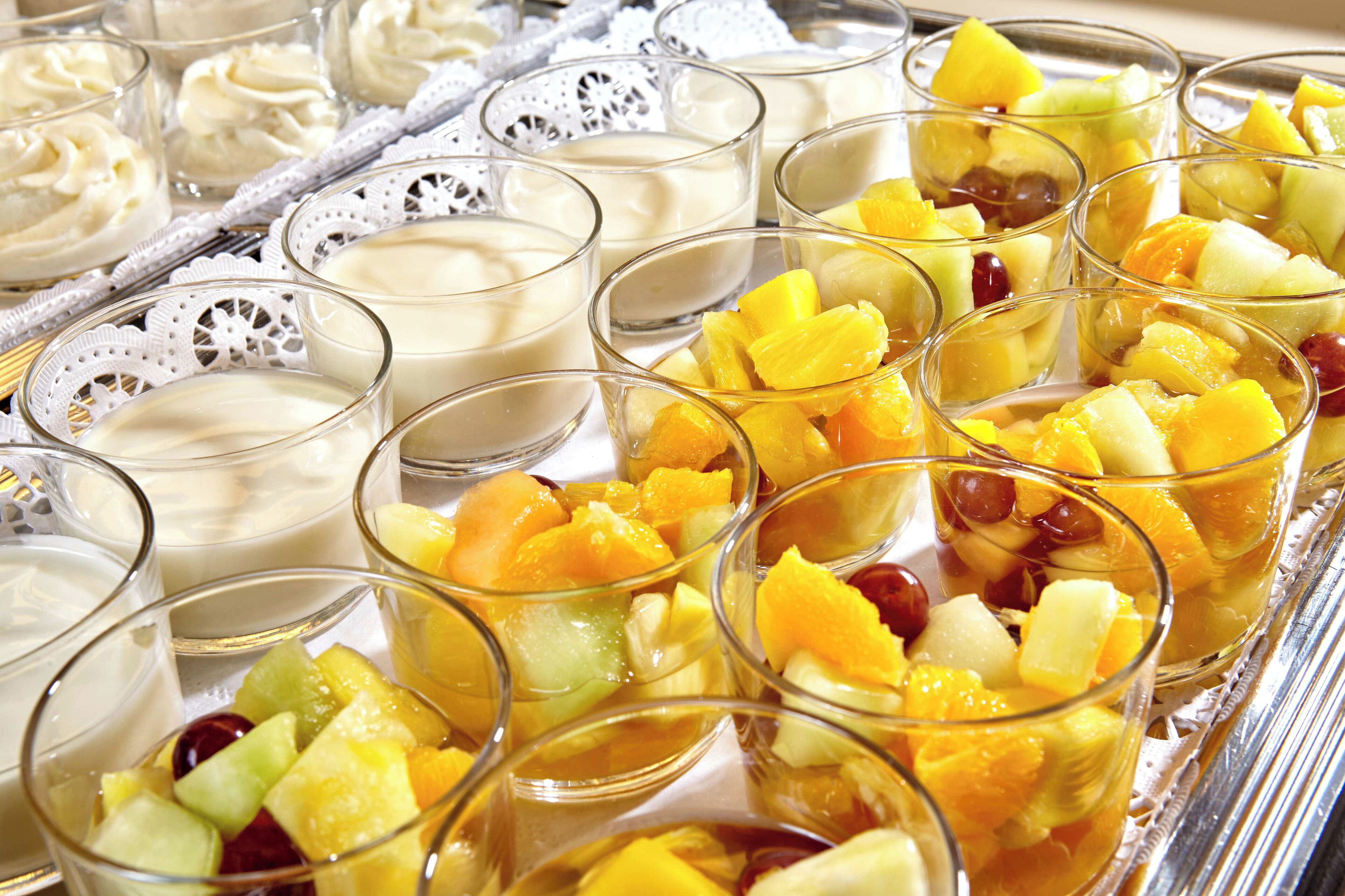 Una bandeja con vasos de fruta y copas de una bebida cremosa, probablemente una opción de postre o refresco.