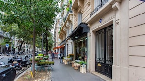 A street with parked cars and a flower shop on the sidewalk. - Résidence Paris MOZART (Paris)