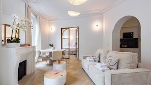 A modern living room with a fireplace, round wooden tables, a sofa, and a dining area. - Résidence Paris MOZART (Paris)