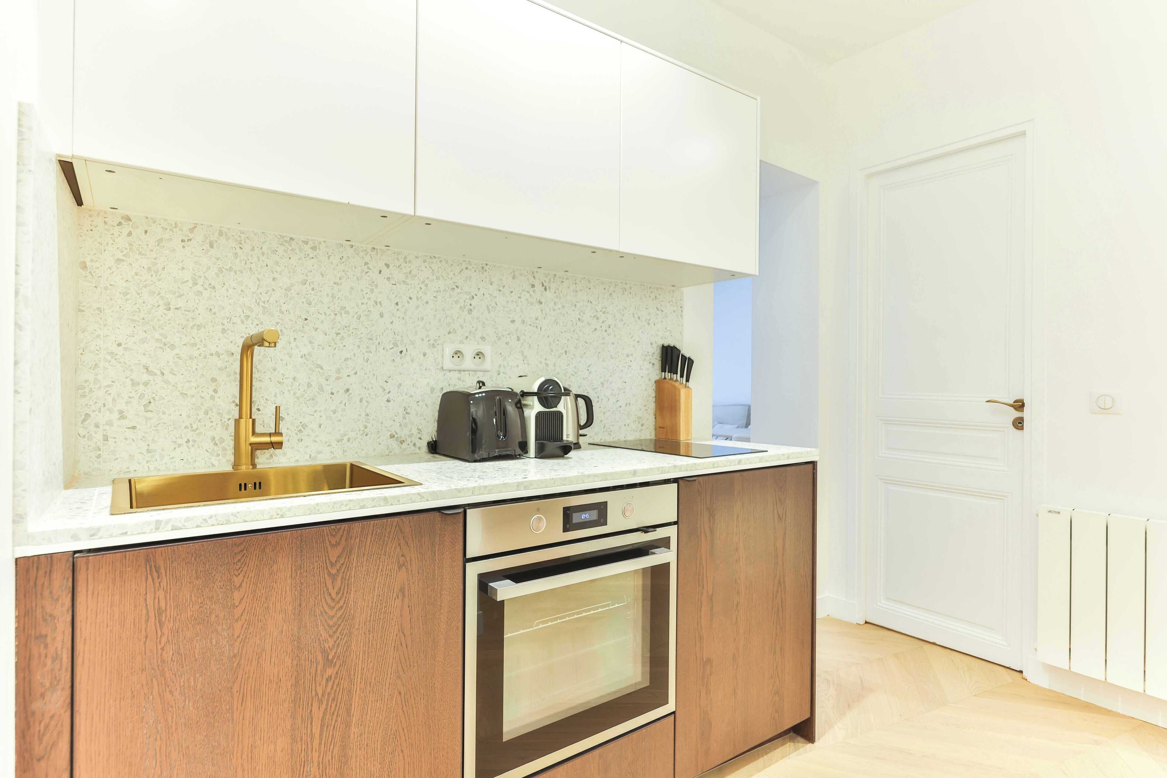 A kitchen with a stainless steel sink, a built-in oven, and a coffee maker.