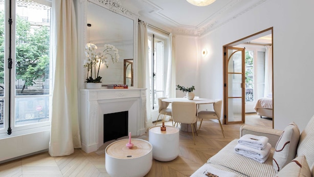 A spacious living room with a fireplace, round tables, and a sofa with towels. - Résidence Paris MOZART (Paris)