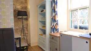 Eine kompakte Küche mit Steinwand, einem blauen Schrank, einem Holztisch und einer Stehlampe.