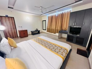 A hotel room with a large bed, a TV, a wardrobe, and a desk. - Hotel Diamond Airport (New Delhi)