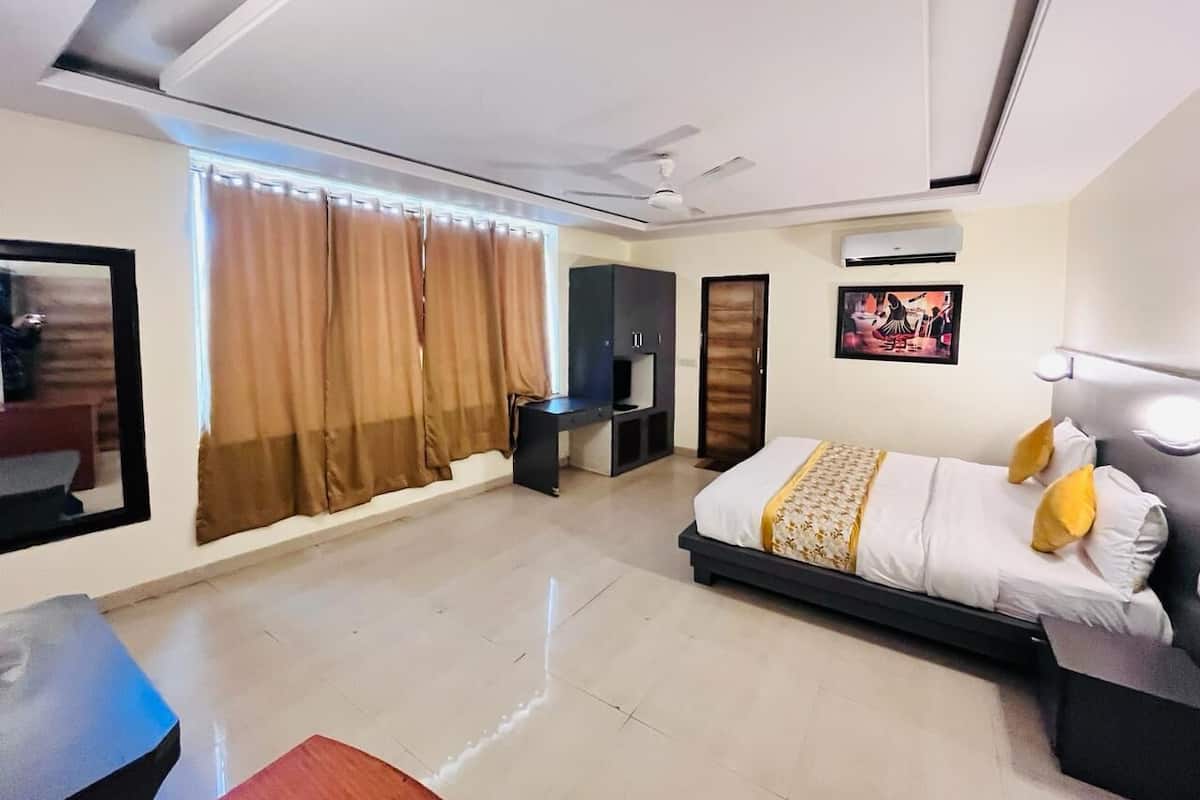 A modern hotel room with a bed, a desk, a wardrobe, and a ceiling fan.