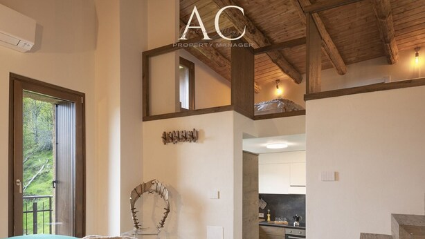 A bedroom with a large bed, a wooden staircase, and a view of a kitchen. - Ecobaita del Cacciatore (Incudine)