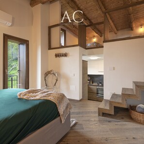 Une chambre avec un grand lit, un escalier en bois et une vue sur la cuisine.