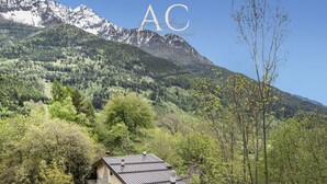 A house with a sloped roof, surrounded by a forest and mountains. - Ecobaita del Cacciatore (Incudine)