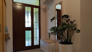 A hallway with a wooden door, a small white cabinet, and a large potted plant. - Villa Hilda (Barban)