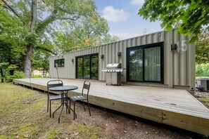 Une terrasse extérieure moderne équipée d’un barbecue, d’une table et de chaises.