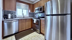 Una cocina moderna con electrodomésticos de acero inoxidable, armarios de madera y salpicadero de azulejos.