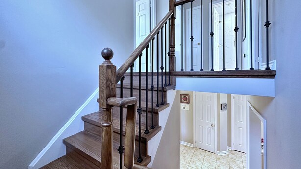 Una escalera de madera con balaustres negros y una puerta blanca al final.