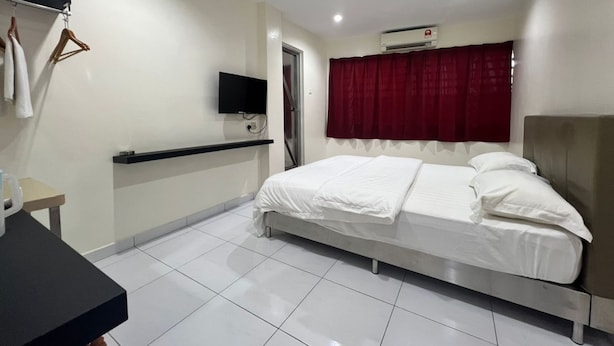 A hotel room with a bed, a TV mounted on the wall, a small table, and a window with a red curtain. - OYO 90994 Hotel Golden Mouse (Ipoh)