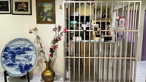 A reception area with a traditional Chinese vase and a blue and white ceramic plate, a barred gate, and framed artwork on the wall. - OYO 90994 Hotel Golden Mouse (Ipoh)