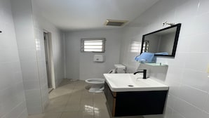 A small, modern bathroom with white tiles, a white toilet, a white sink with a black countertop, and a mirror above the sink. - OYO 90994 Hotel Golden Mouse (Ipoh)