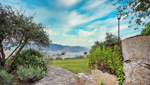 A stone pathway leading to a grassy area with a view of a city and mountains in the distance.
