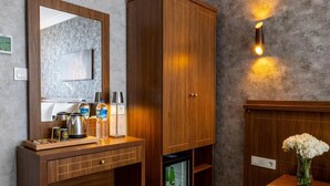 A hotel room with a wooden wardrobe, a minibar, a mirror, and a wall-mounted light fixture. - Diamond Beyazıt Hotel (Istanbul)