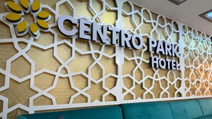 Zona de recepción de un hotel con un diseño geométrico en la pared y un sofá color turquesa.
