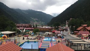 Un paisaje montañoso con piscina, parque infantil y varios edificios con tejados rojos.