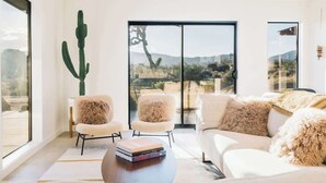 A modern living room with a large window, a cactus, and a view of a desert landscape.
