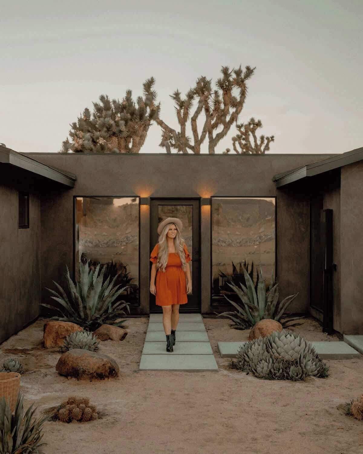 Un edificio moderno con jardín desértico, con cactus y cielo despejado.