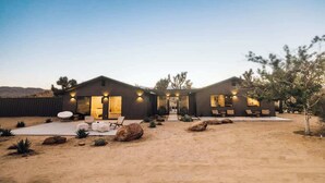 A modern two-story house with a desert landscape.