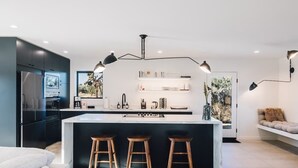 A modern kitchen with a central island, black cabinets, and pendant lighting.