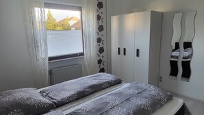 Une chambre à coucher avec un lit, une armoire et une fenêtre avec des rideaux.