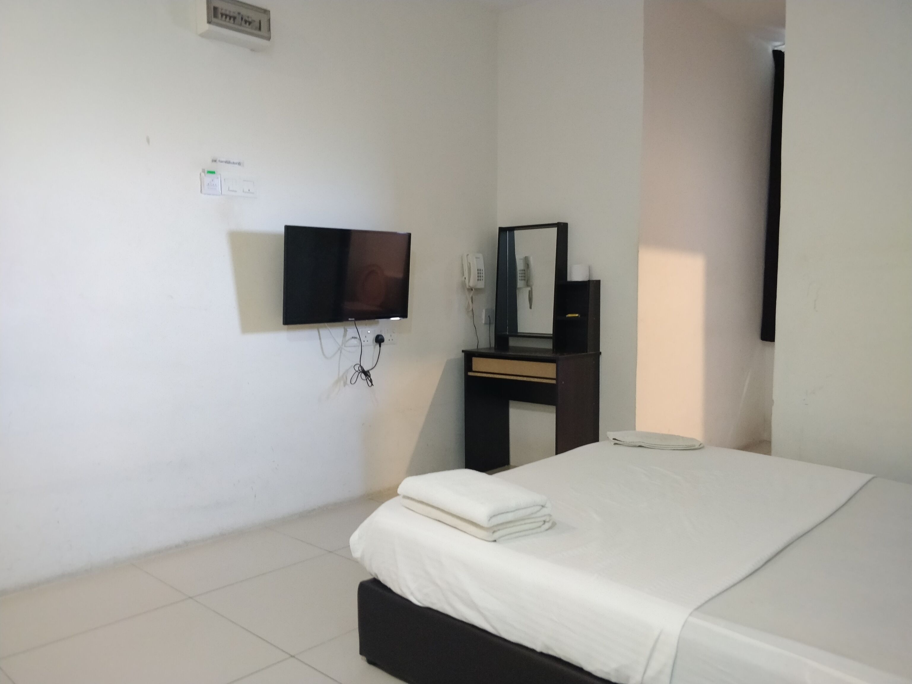 Habitación de hotel con cama, escritorio con espejo, teléfono y televisión instalada en la pared.