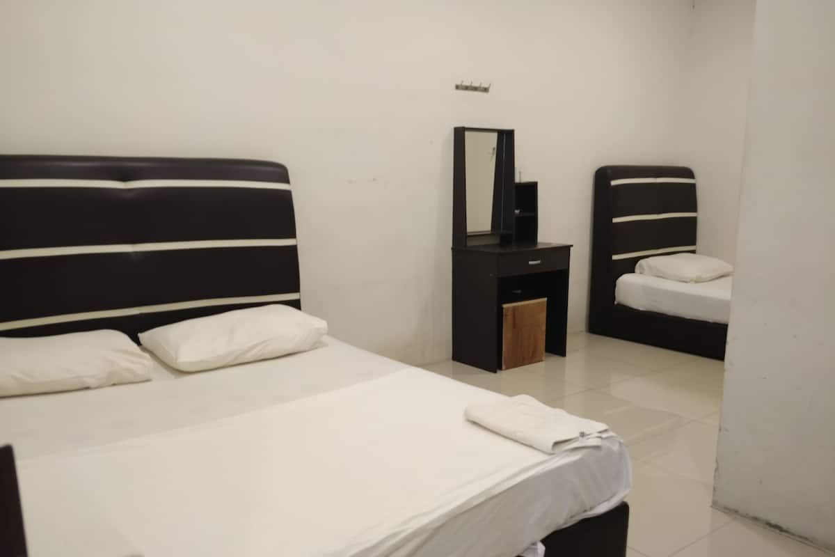 A hotel room with two beds, a small desk, a mirror, and a white wall.