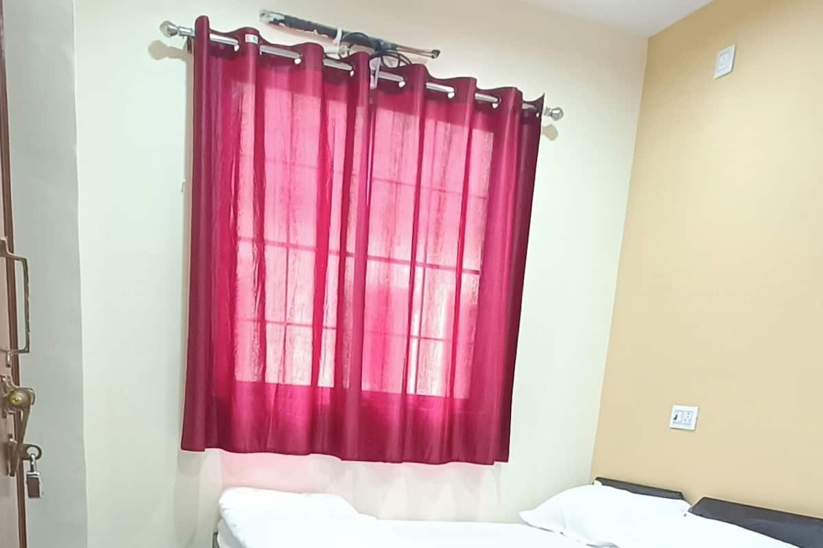 Un dormitorio con cama, ventilador de techo y ventana con cortinas rojas.