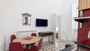 Een compacte woonruimte met een eethoek, een televisie, een spiegel en een kitchenette.
