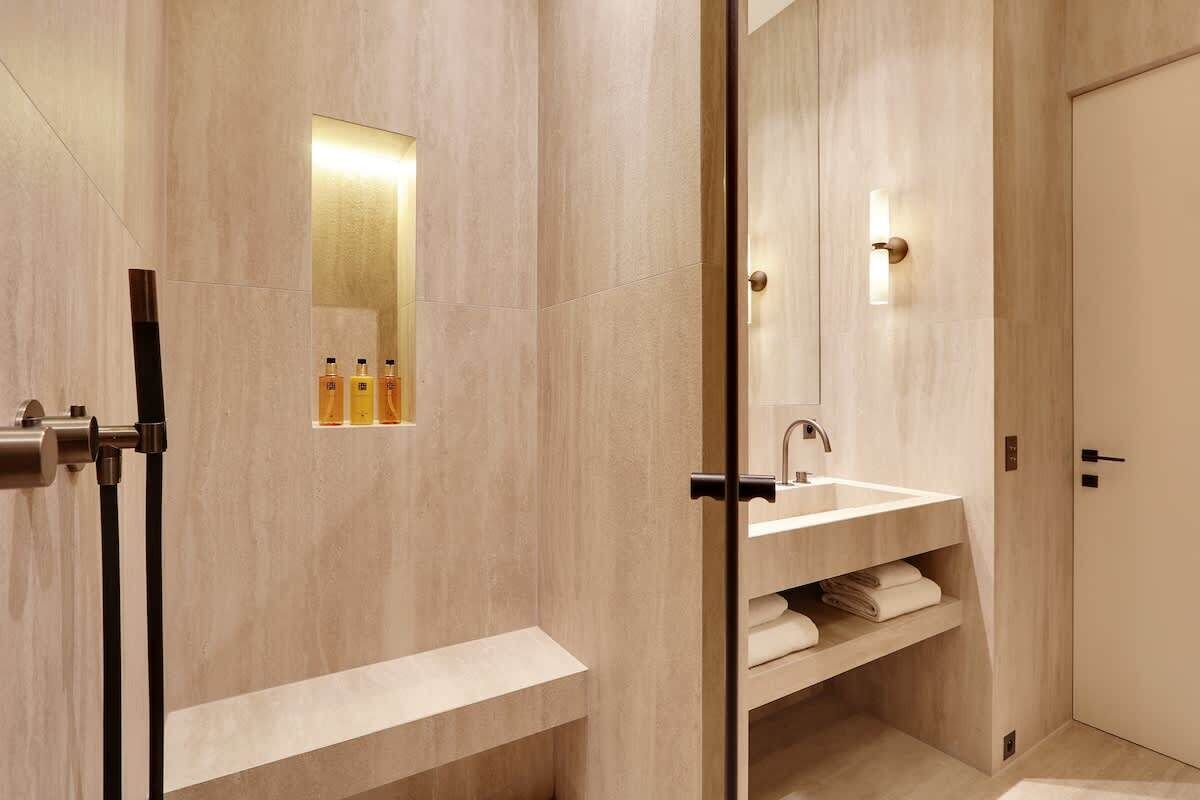 Un baño moderno con un espejo grande, un lavabo y una zona de ducha.