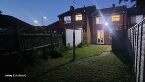 Ein Wohnhaus mit Vorgarten, Holzlattenzaun und Backsteinfassade.