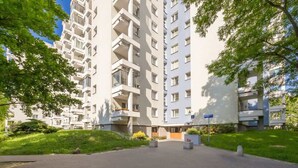 A modern apartment building with multiple balconies, a parking area, and greenery. - Bright Apartment with Balcony | Workplace, Close to Metro (Warszawa)