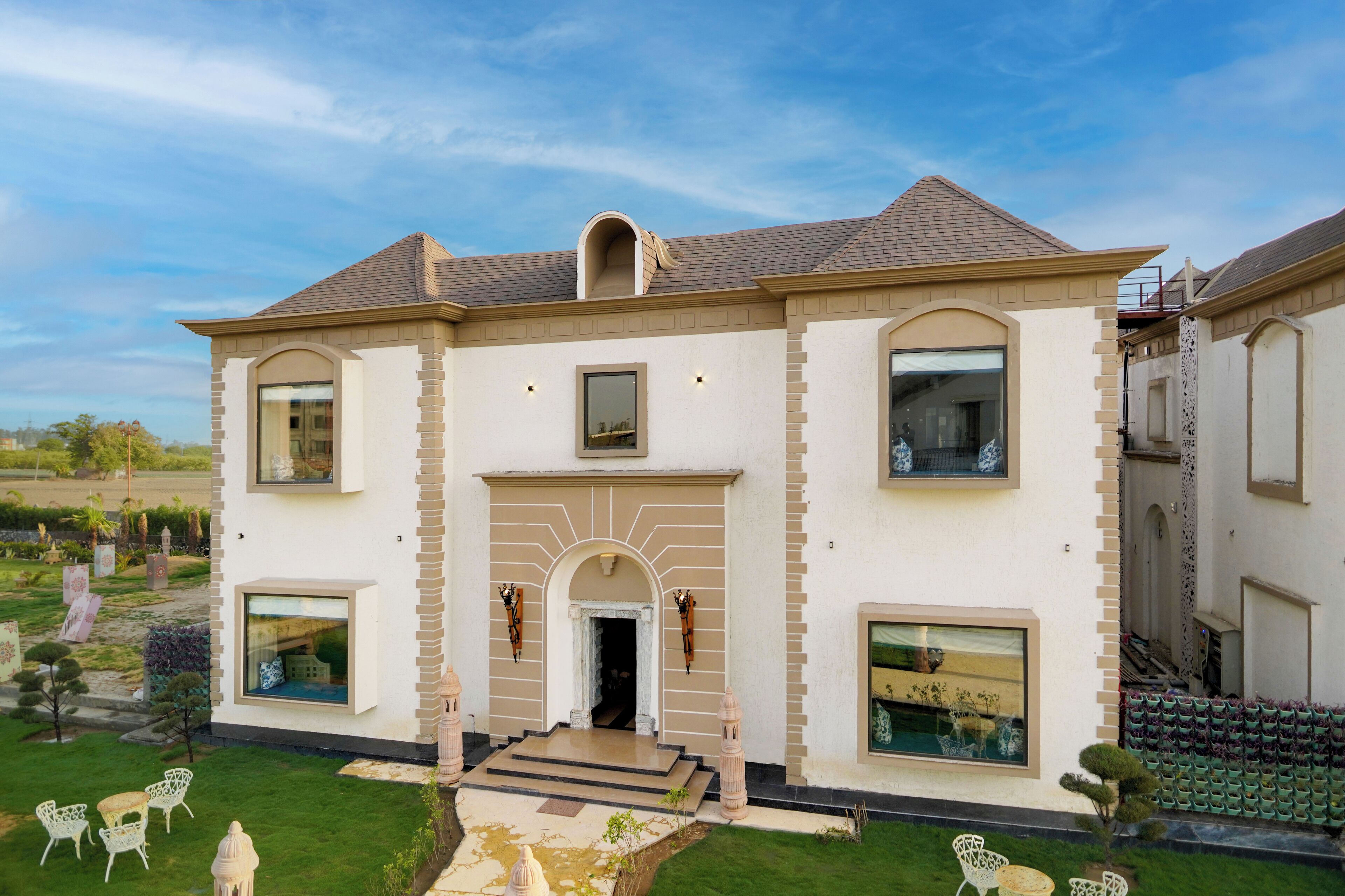A two-story house with a symmetrical facade, large windows, and a central entrance with steps.