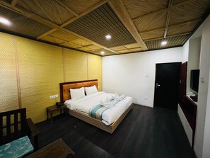 A hotel room with a bed, bedside table, and a television. - Thongsal (Leh)