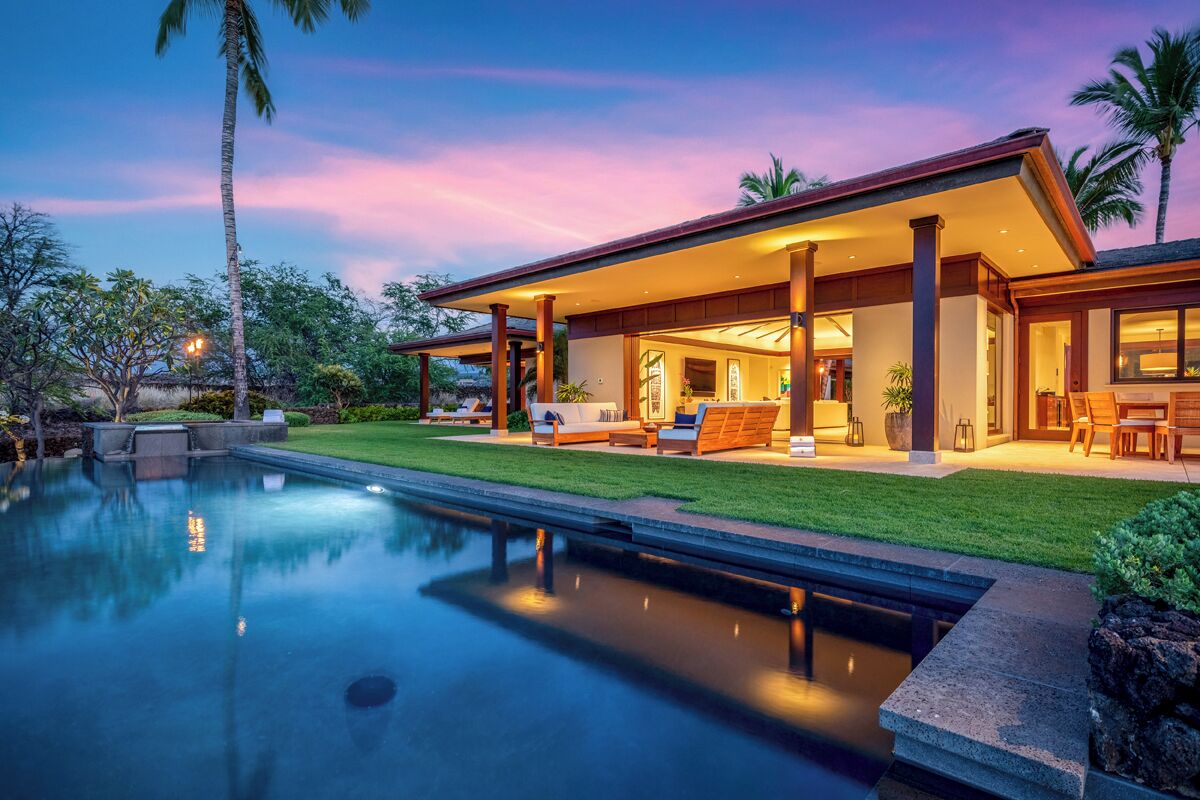 Et moderne hus med pool, udendørs møbler og en veloplyst terrasse.