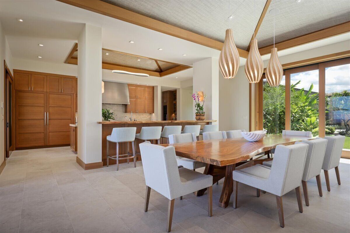 A modern kitchen with a central island, white chairs, and pendant lighting.