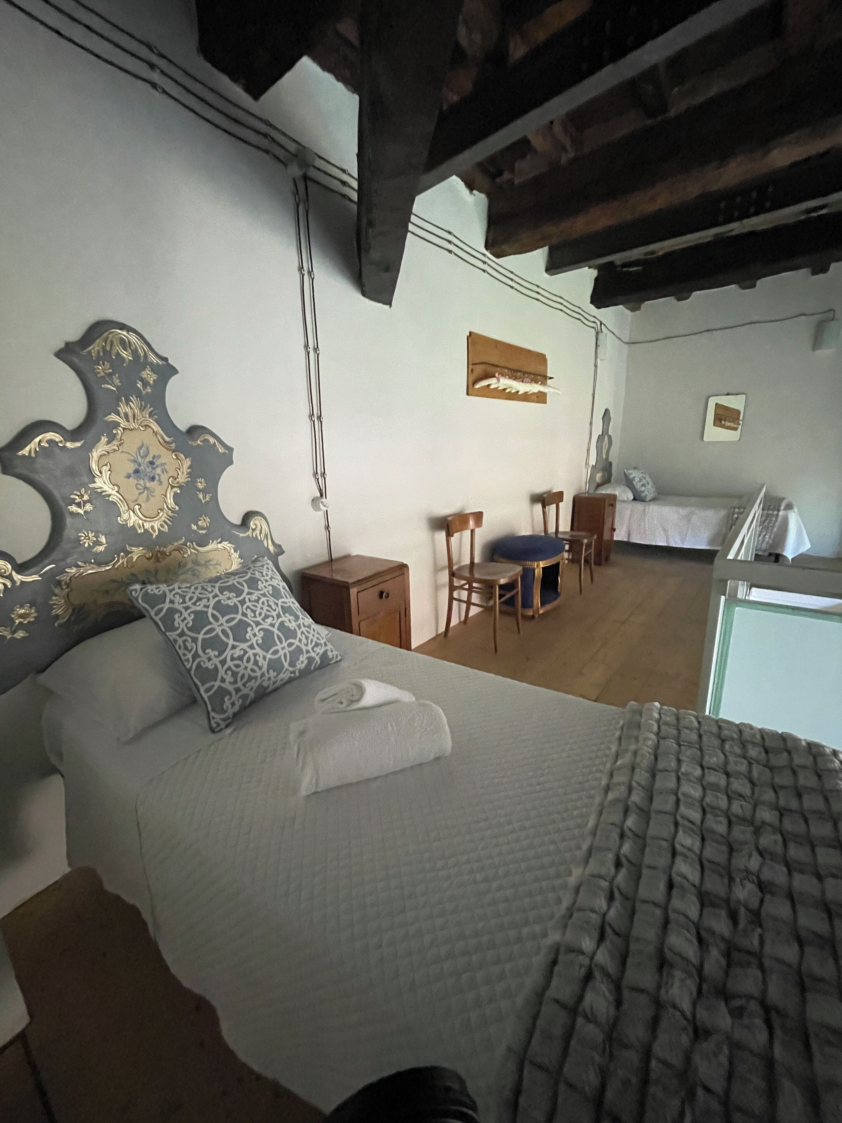 A bedroom with a large bed, a wooden headboard, a desk, and a chair.
