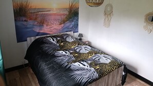 A bedroom with a bed, a wall-mounted artwork of a sunset, a hanging light fixture, and a dreamcatcher decoration. - Pleine Nature, Maison de Campagne à 10 min zoo Beauval Mareuil/cher (Mareuil-sur-Cher)
