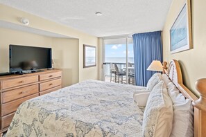 Relax in comfort with a large bed featuring a world map quilt, a flat-screen TV, and a balcony with ocean views.