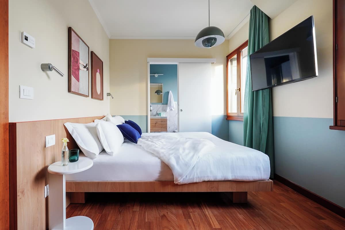 A hotel room with a bed, bedside table, TV, and a view of the bathroom.