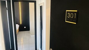 Een gang met een deur met daarop '301' en een zichtbare kamer op de achtergrond.
